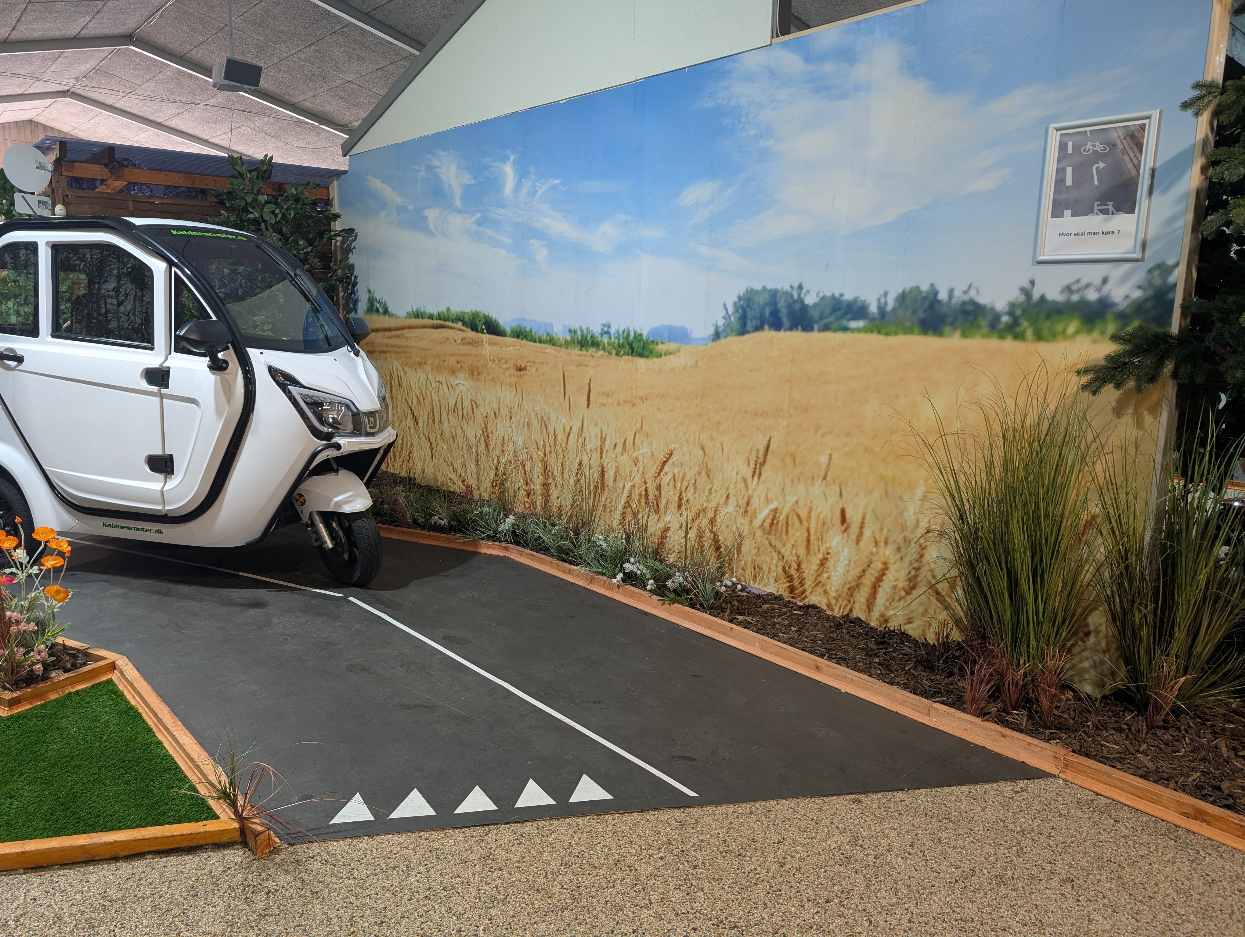 ASSP showroom i Hobro — hvid kabinescooter med dansk kornmark-scenografi